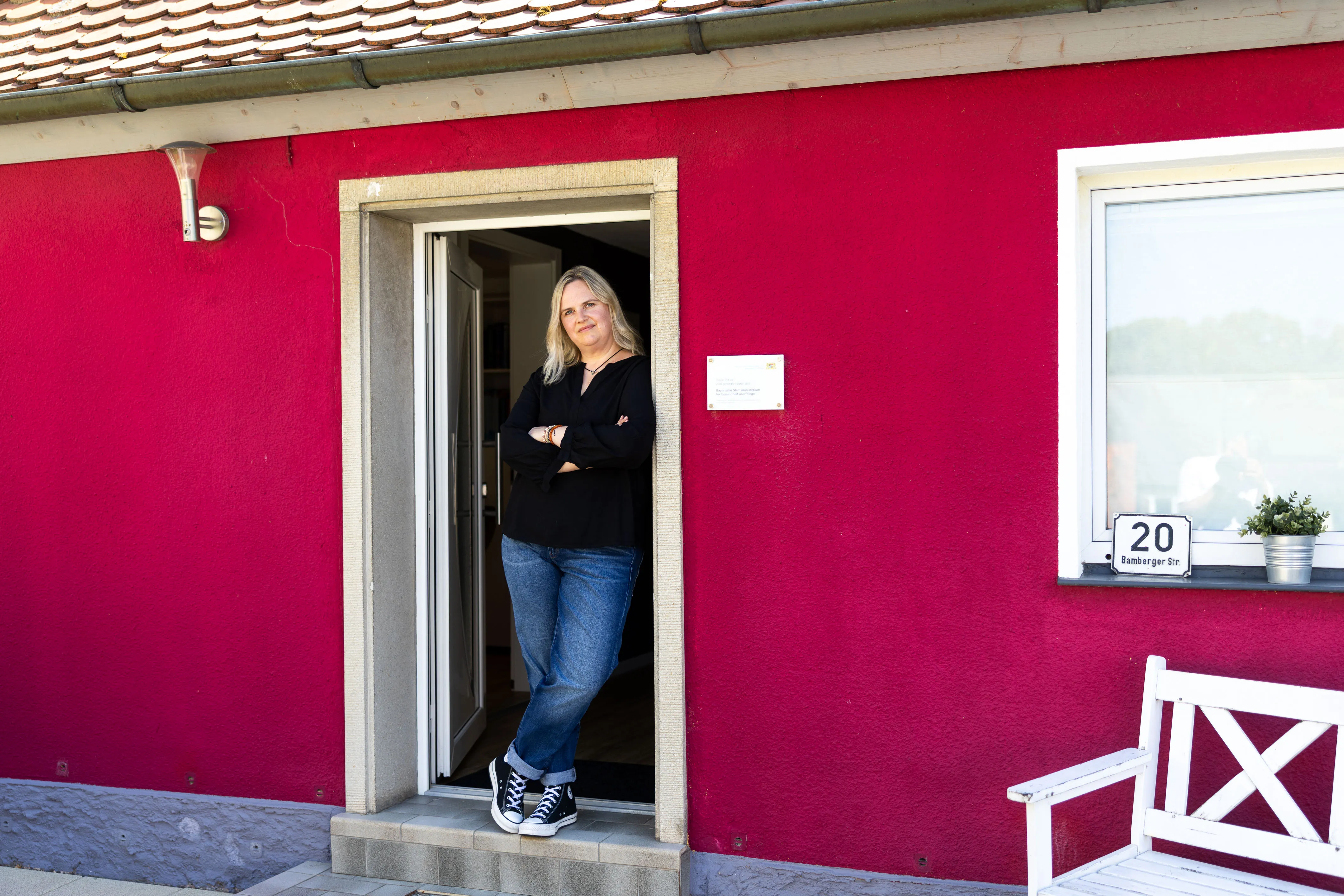Das rote Praxishaus in der Bamberger Straße 20 mit Eingangstür und weißer Bank davor