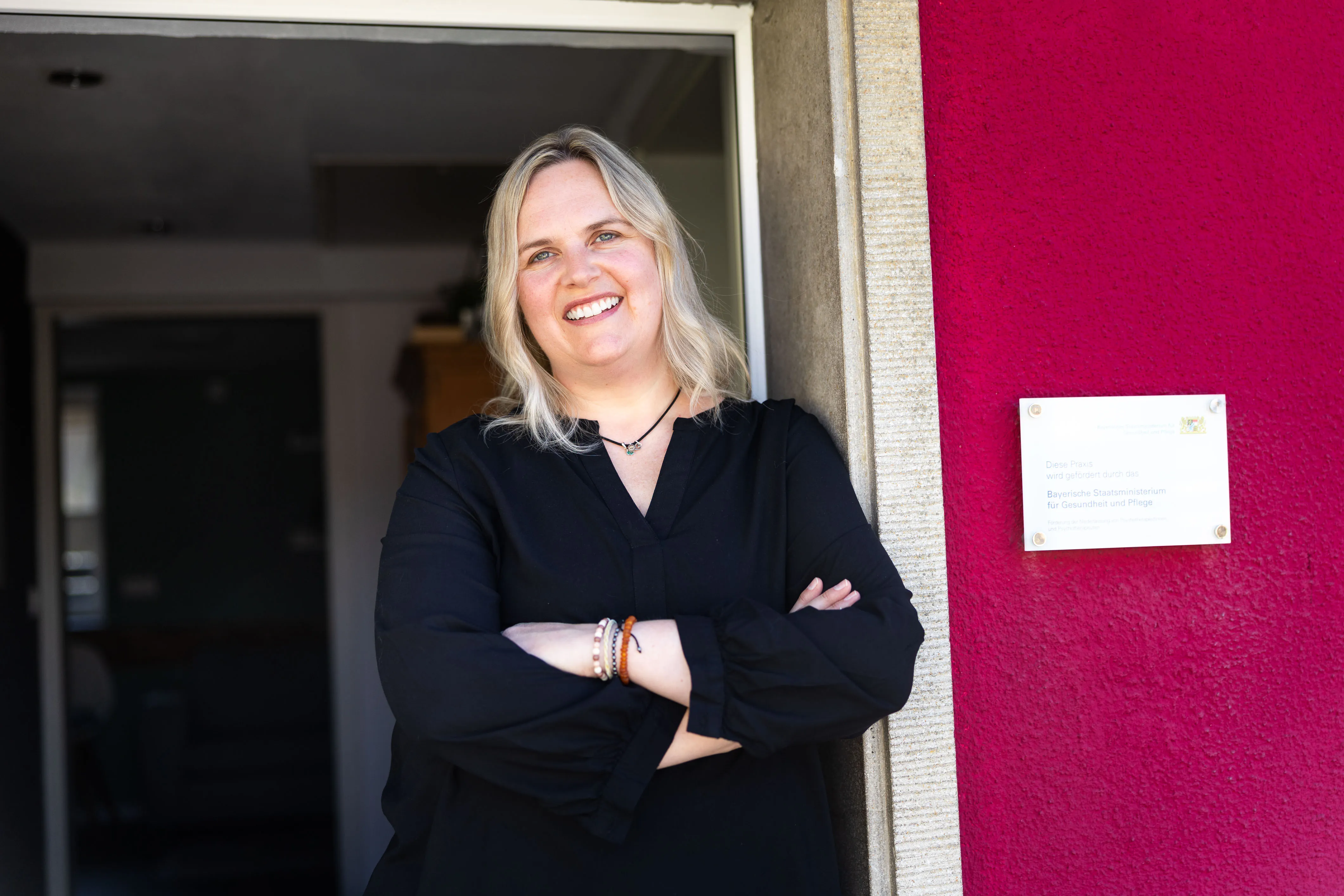 Nicole Rodammer steht lachend in der geöffneten Tür ihrer Praxis