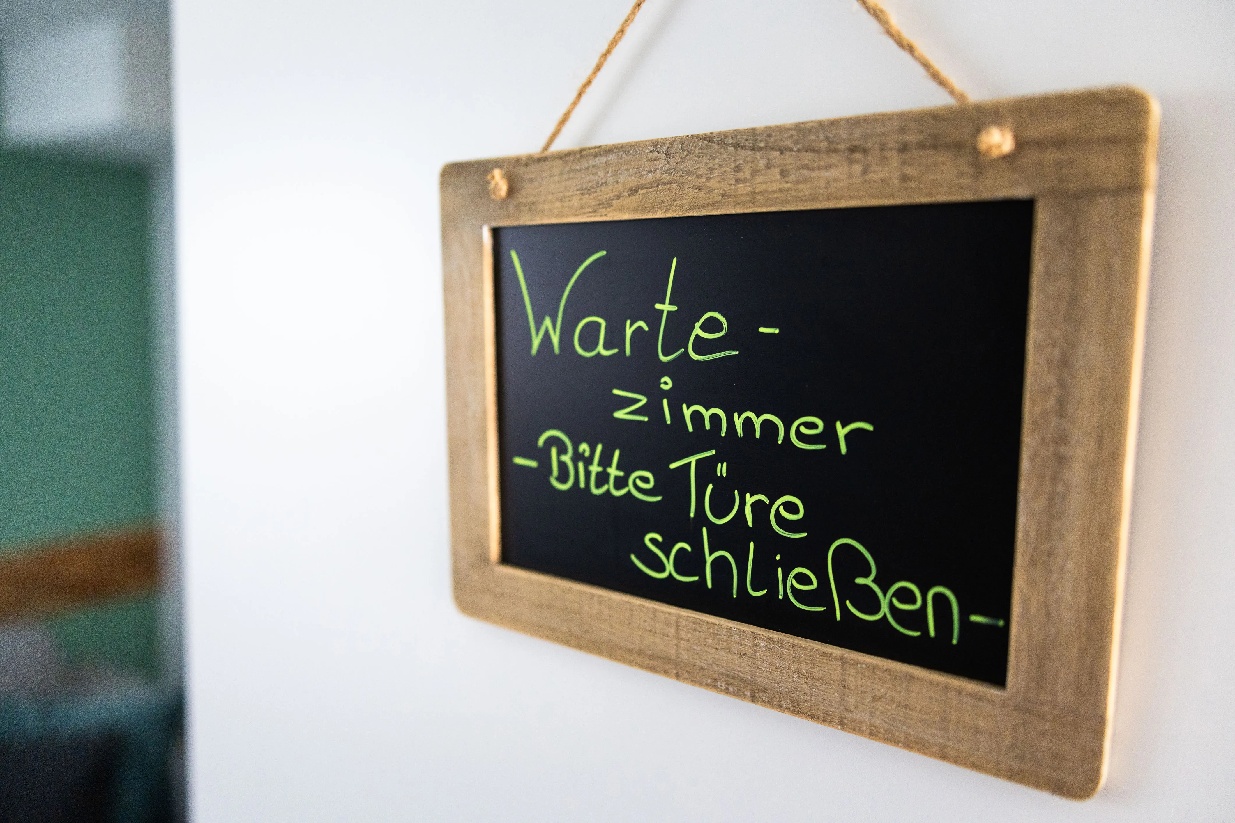 Handbeschriebene Kreidetafel an der Tür: Wartezimmer, bitte Türe schließen
